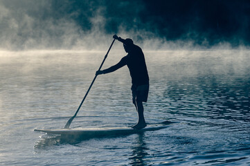Surfer paddling on the board in fog