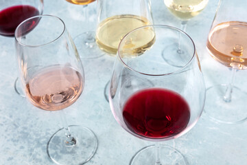 A glass of red wine at a tasting at a winery. Various colors and shapes of glasses