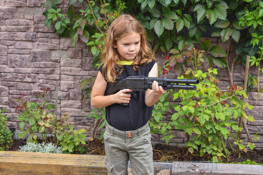 child girl with a rifle guards her own house photo without processing