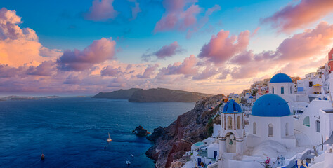 Beautiful panorama view of Santorini island in Greece at sunrise with dramatic sky. Stunning Oia cityscape, sunset colors sky with blue domes with white architecture. Amazing travel vacation landscape