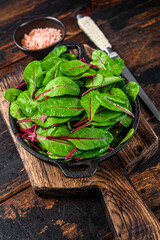 Fresh raw chard leaves,  mangold, swiss chard in a pan. Dark Wooden background. Top view
