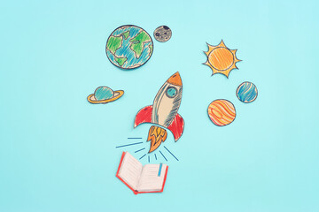 Painted rocket and planets over pastel blue background