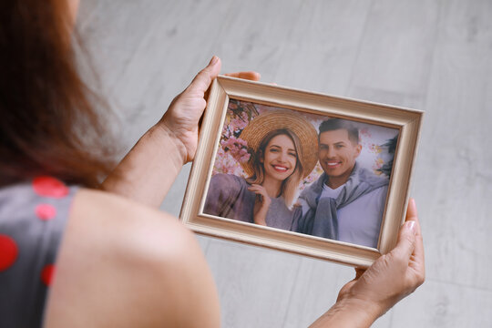 Woman holding framed photo of happy couple indoors, closeup