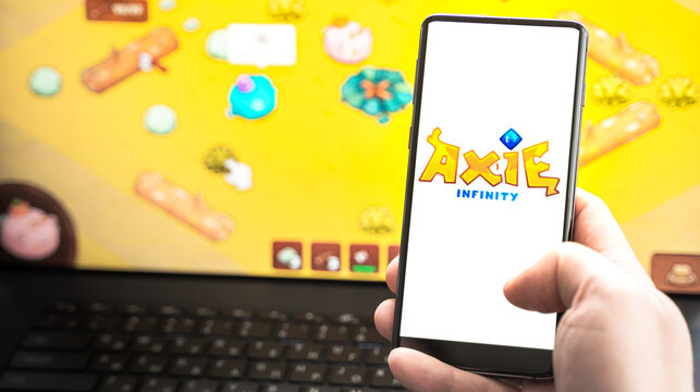 Russia Moscow 30.05.2021.Logo,screenshot of blockchain nft ethereum cryptocurrency game Axie in laptop,mobile phone.Man playing,collecting,creating crypto pet,heroes. Earning digital money tokens AXS
