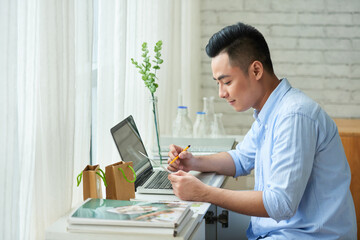 Happy young businessman checking orders made via website of his online organic soap shop