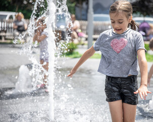 A little girl chills in a fountain on a hot summer day.