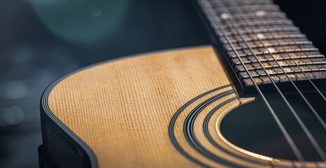 Fototapeta premium Acoustic guitar on a black background in the light of a spotlight.