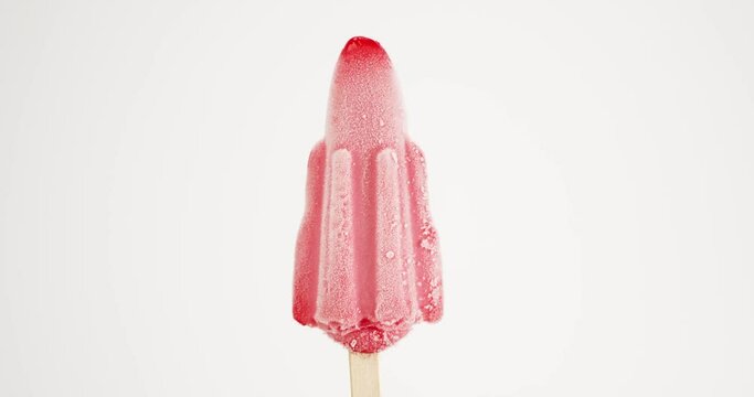 Close-up detail Front view, Time-lapse red rocket flavored ice cream popsicle stick melts isolated on white background.