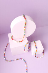 Necklace and bracelet made from beads and pearls on purple pastel cubes.