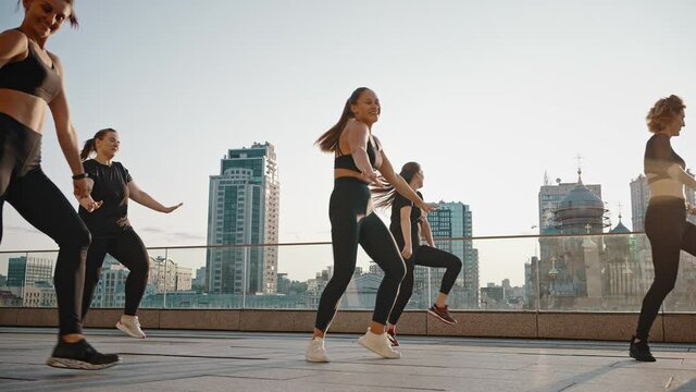 Group of girls is practicing outdoor sports dances, like-minded women are training on the street. Young women dancing zumba on the city background
