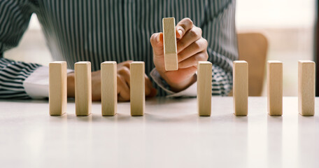  Businesswoman protect wooden block fall to planning and strategy in risk to business Alternative...