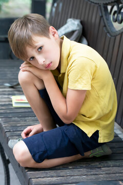 Sad little boy sits on a park bench.