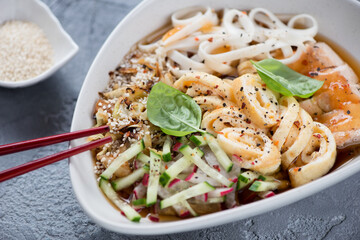 Bowl of korean traditional kuksi soup with chicken meat, studio shot on a grey concrete surface, close-up