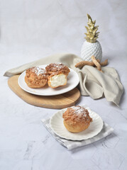 luxury home made chilled vanilla cream puff pastry choux with sugar powder on wood plate and cloth in white marble background dessert halal menu