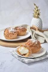 luxury home made chilled vanilla cream puff pastry choux with sugar powder on wood plate and cloth in white marble background dessert halal menu
