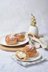 luxury home made chilled vanilla cream puff pastry choux with sugar powder on wood plate and cloth in white marble background dessert halal menu
