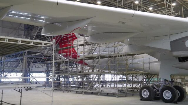 Workers painting airplane in hangar on scaffolding