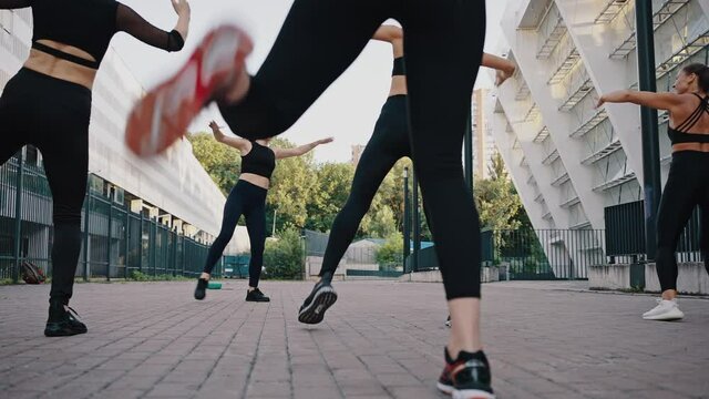 Low angle view of dancing aerobic class of a womens modern dances. Group of girls are dancing outdoor on a city street in a sport wearing