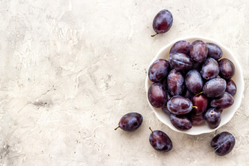 Ripe garden plums in bowl. Cherry fruit with leaves. Top view