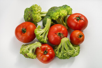 Ripe red tomatoes and broccoli slices on a white background. Harvest in the fall. Isolated