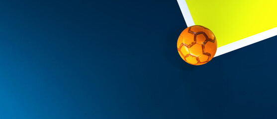 Orange futsal soccer ball in the corner of a blue, yellow indoor field background