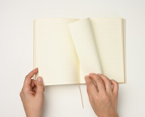 two female hands hold an open notebook with blank white sheets on a white background