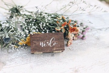 Boho wedding still life. Jewellery wooden gift for rings with white lettering. Colorful floral...