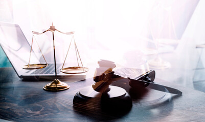 Justice and law concept.Male judge in a courtroom with the gavel, working with, computer and docking keyboard, eyeglasses, on table in morning light