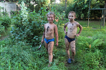 Two boys posing soiled in mud