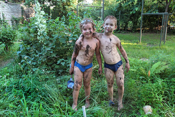 Two boys posing soiled in mud