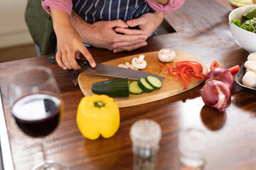 Happy diverse couple in kitchen preparing food together chopping vegetables