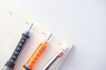 Insulin pens and a planner on white background 