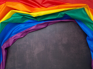 The rainbow flag (LGBT) is on a cement floor with space for text. Top view. Flat lay. Love concept