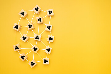 Network, Teamwork, and unity concept. Top view of wooden blocks with black human icons laid scattered on a yellow background, Flat lay, space for text