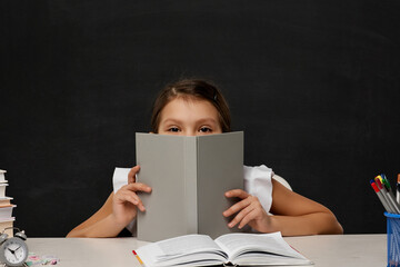 Obraz premium little child girl cover her face by the book