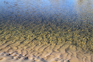 The sandy coast flows smoothly into the water