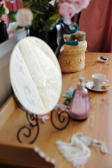 Beautiful bedroom interior. Women's boudoir. Cosmetic mirror, perfume bottle, a wicker hat box and white porcelain tea cup.