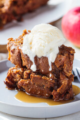 Apple bread with a scoop of ice cream and maple syrup on a gray plate. Autumn fruit pie, gray background.