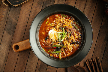 Korean beef ramen spicy noodle soup with chopsticks on a wooden background