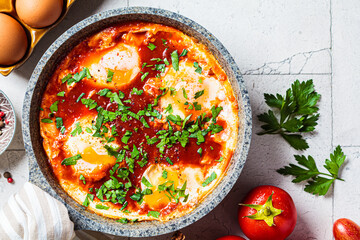 Traditional Israeli shakshuka in gray frying pan. Fried eggs in tomato sauce, close-up.