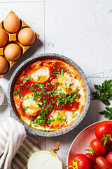 Traditional Israeli shakshuka in gray frying pan. Fried eggs in tomato sauce.