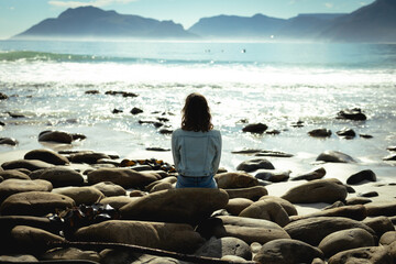 Mixed race woman sitting on sunny day by seaside