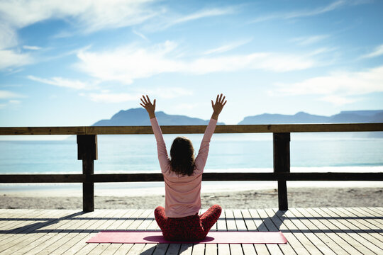 Mixed race woman practicing yoga on sunny day by seaside