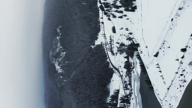 Vertical flyover above Frumoasa Dam, Romania during winter, blanketed with snow