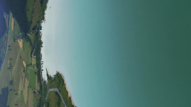 Vertical format aerial clip above large reservoir behind Frumoasa Dam, Romania