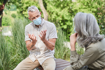 Fototapeta premium Mature loving couple wearing protective masks spending time in nature