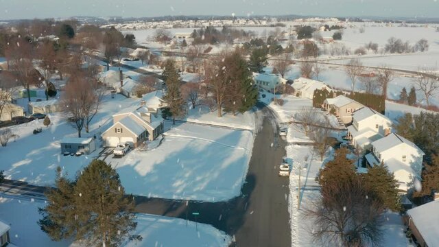 Winter snow on sunny day. Aerial tracking shot through neighborhood housing development.