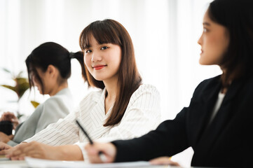 Fototapeta premium Asian business hold a small meeting inside the office or conference room. Brainstorm to exchange ideas. There are stock boards Laptops and tablets are communication tools. Unity teamwork concept.
