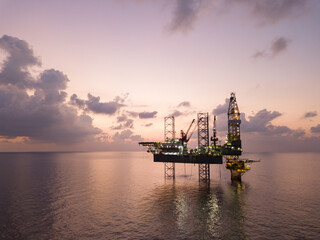 Obraz premium Offshore Jack Up Rig in The Middle of The Sea at Sunset Time for Petroluem Exploration and Production