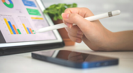 Business and financial diagram on the screen, office desk background. Female worker analyzing...